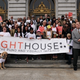 LightHouse staff, students, and supports stand outside San Francisco City Hall holding a LightHouse banner