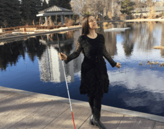 Dr. M. Leona Godin stands on a dock holding her white cane