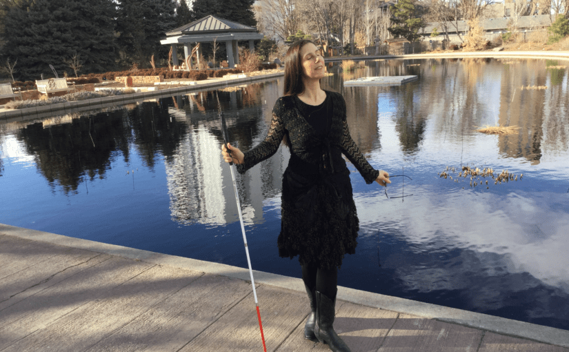 Dr. M. Leona Godin stands on a dock holding her white cane