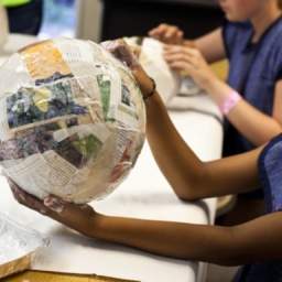 A child holds a balloon covered in papier-mâché at a previous Enchanted Hills Camp session