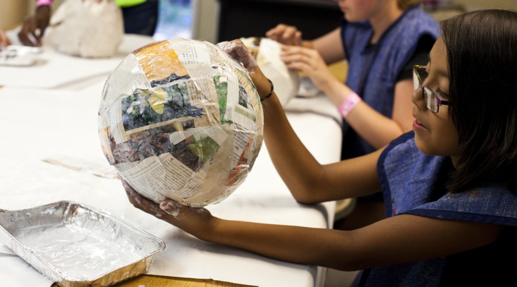 A child holds a balloon covered in papier-mâché at a previous Enchanted Hills Camp session