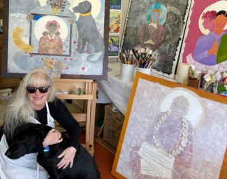 Catherine in an art studio surrounded by her paining and hugging her guide dog, Andrea