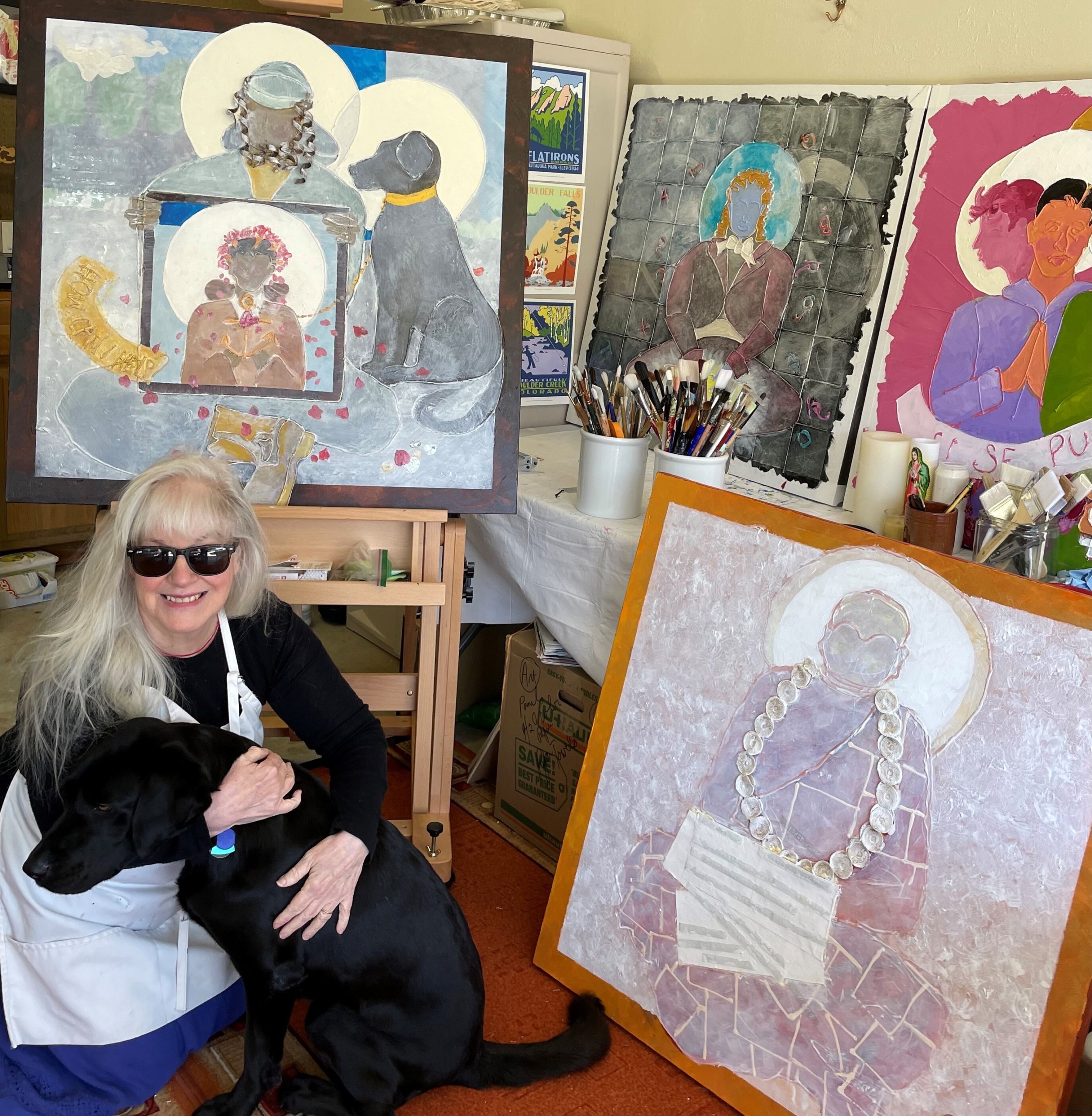 Catherine in an art studio surrounded by her paining and hugging her guide dog, Andrea