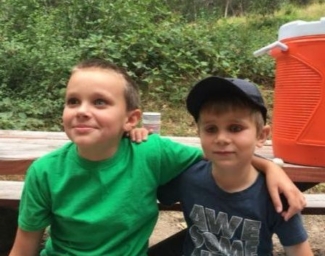 Two kids sit on a bench and smile at EHC