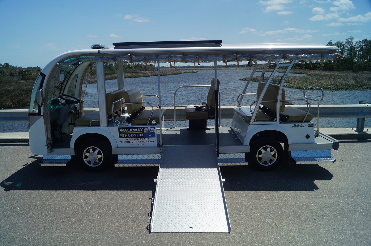 A white electric shuttle bus with wheelchair ramp extended