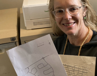 Orientation and Mobility specialist, Anegla Reynolds, poses with two TMAPs she has embossed for clients in Australia