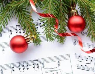 An image of sheet music, red ribbon, a red ornament, and pine tree branches