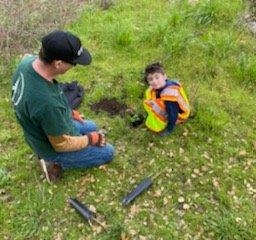 Two volunteers, a man and a child, planting a tree at Enchanted Hills Camp in Napa