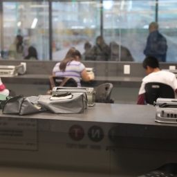 Three Perkins Braillers sit on a desk in focus in the foreground, three students working at three other Perkins Braillers are out of focus in the background