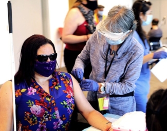 A nurse preps a person to receive a COVID-19 shot at LightHouse in 2021
