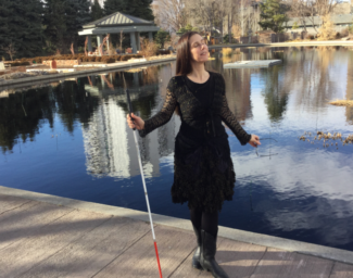 Dr. M. Leona Godin stands on a dock holding her white cane