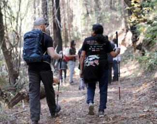 A group of people with white canes hike a trail at Enchanted Hills Camp