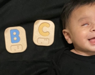 Little Learner is laying down next to ABC Braille blocks.