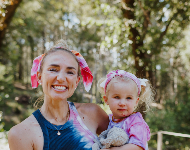 Amanda stands outside and holds Little Learner. Both wear handkerchiefs tied in their hair