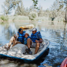 Little Learner sits between Shruti and adult family member on a paddle boat in the water