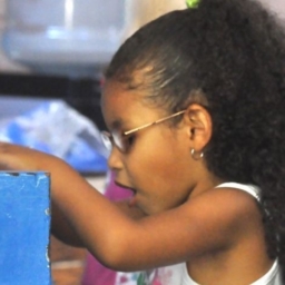 A little girl wearing glasses plays on a toy piano