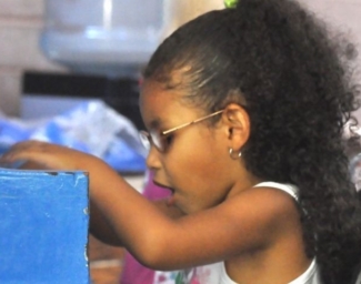 A little girl wearing glasses plays on a toy piano