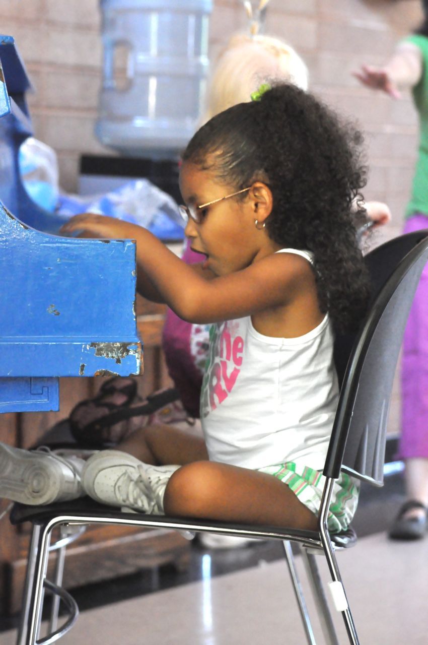 A little girl wearing glasses plays on a toy piano