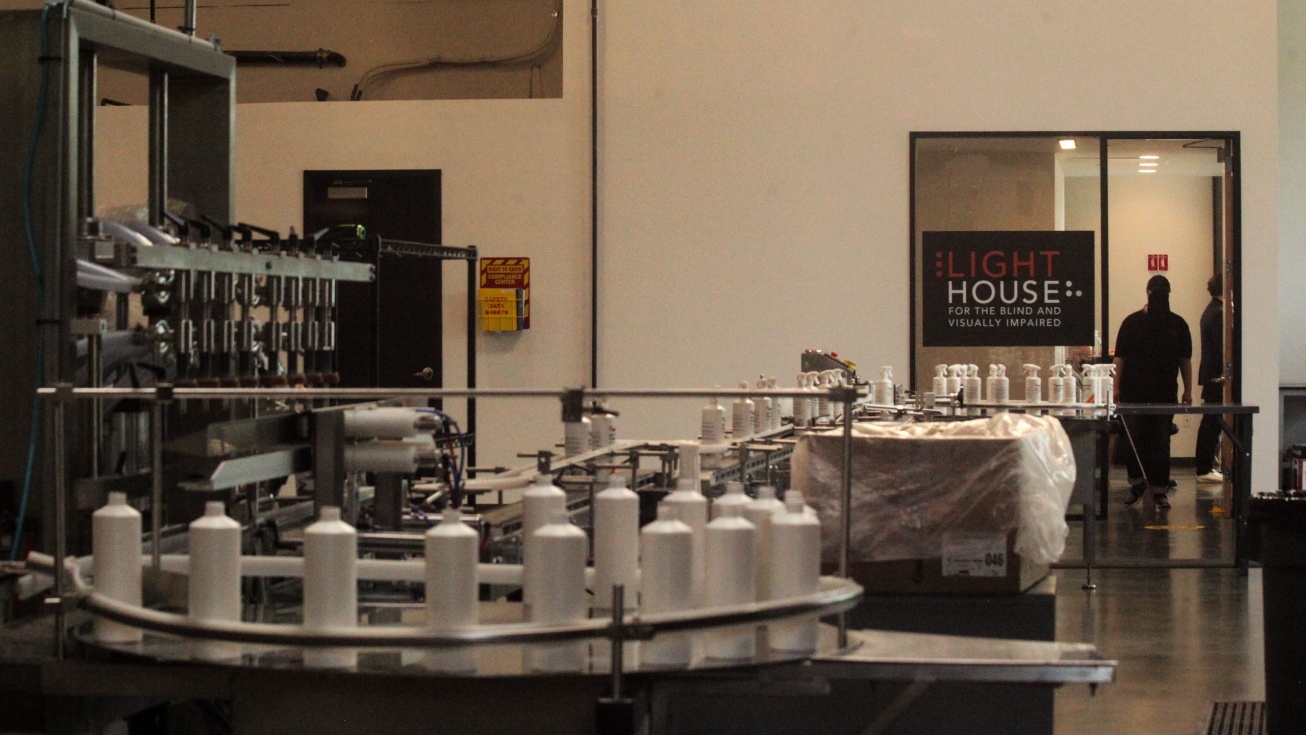 A shot of the manufacturing floor inside the LightHouse Sirkin Center, an employee with a white cane can be seen in the background