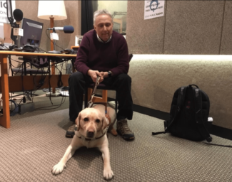 Stephen Kuusisto, blind poet and the first guest speaker in the Writers Workshop, sits at a desk with his guide dog