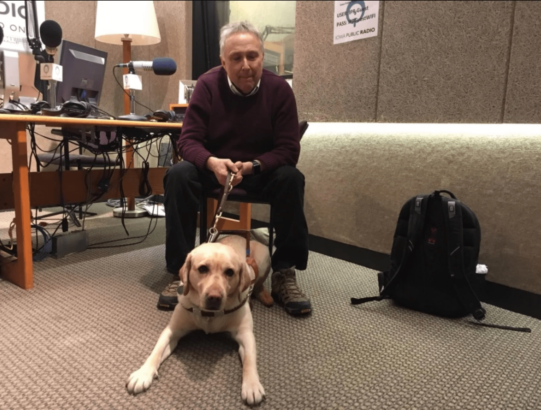 Stephen Kuusisto, blind poet and the first guest speaker in the Writers Workshop, sits at a desk with his guide dog