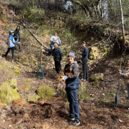 Federal Reserve Bank employees take a break from clearing the archery range at EHC to turn towards the camera and smile.