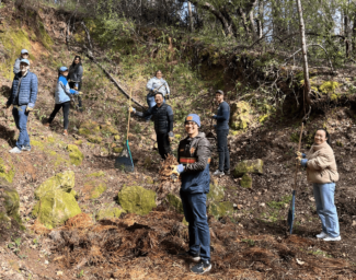 Federal Reserve Bank employees take a break from clearing the archery range at EHC to turn towards the camera and smile.