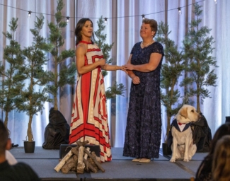 Keynote Speaker Rebecca Alexander and LightHouse CEO Sharon Giovinazzo stand together on stage - the stage is decorated with pine trmees and bistro lights to bring the essence of camp to the Grand Ballroo