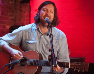Graham Norwood singing while playing guitar