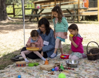 Little Learers and a parent playing on a blanket at Little Learners Family Camp