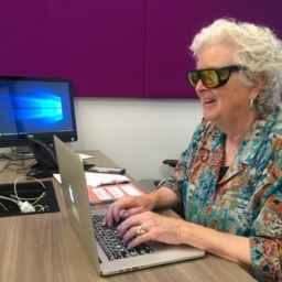 A student wearing yellow fitover sunglasses types at a laptop in a LightHouse tech lab