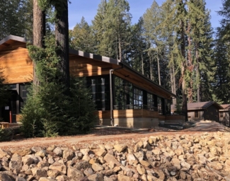 A new structure at EHC with external wood paneling, large windows, and is surrounded by redwood trees and newly paved paths