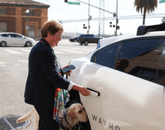 LightHouse CEO Sharon G. and guide dog Pilot getting into an autonomous vehicle