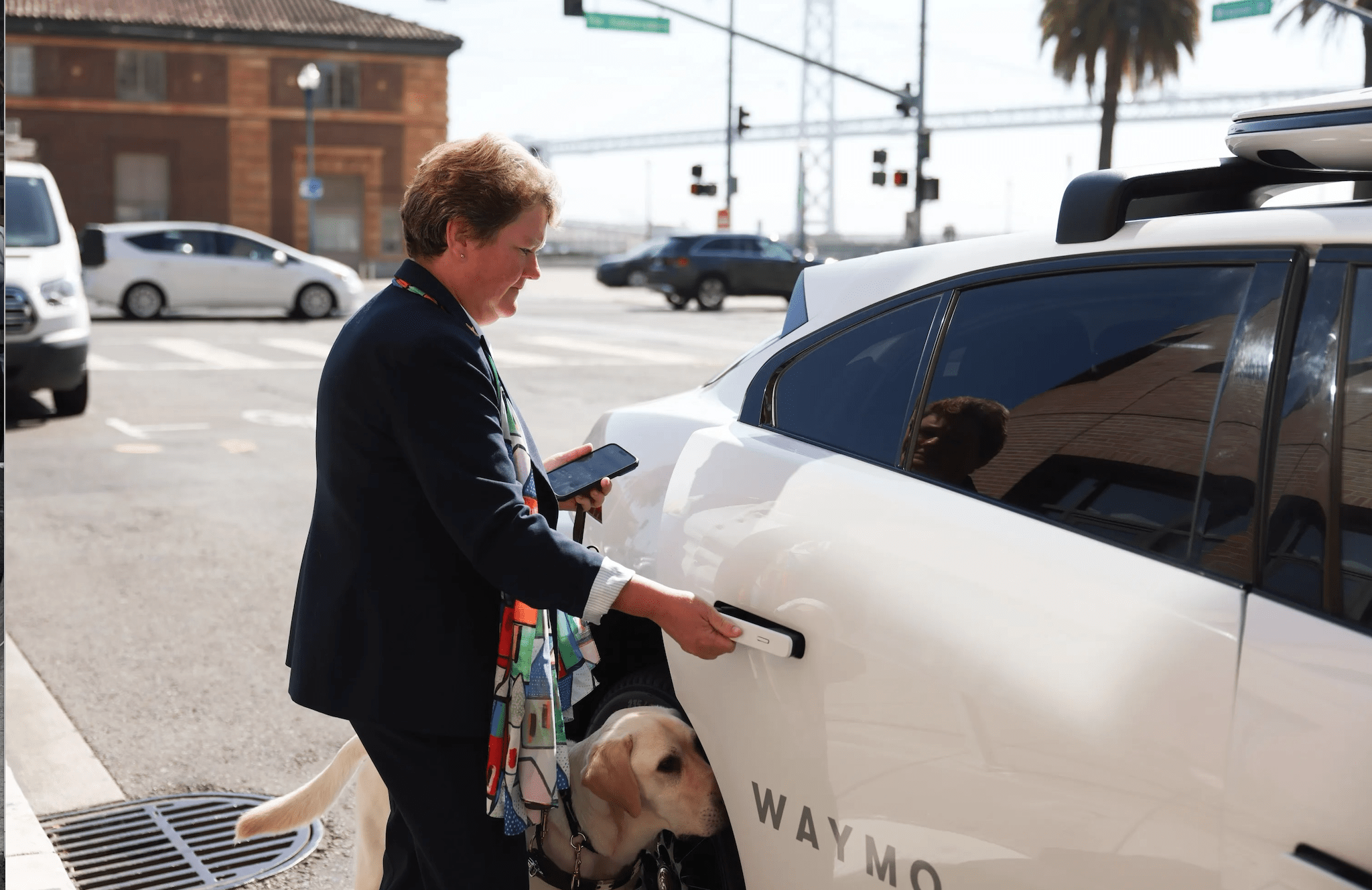 LightHouse CEO Sharon G. and guide dog Pilot getting into an autonomous vehicle