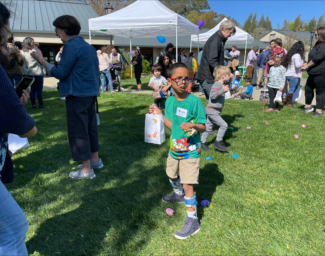 LightHouse Little Learners holding spring-themed decorated bags hunt for beeping eggs at an accessible egg hunt at last year's Spring Celebration