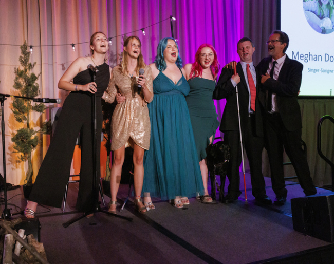 EHC staff and longtime friend and camper pose together on stage